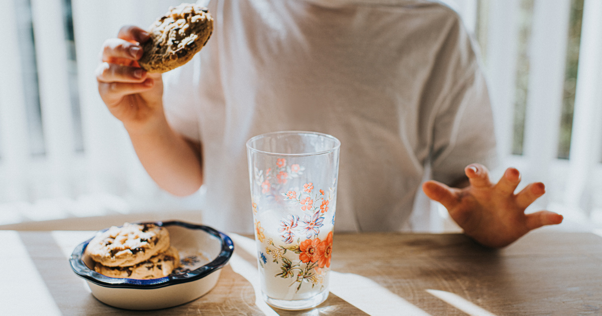 foto van een persoon die melk met koekjes eet