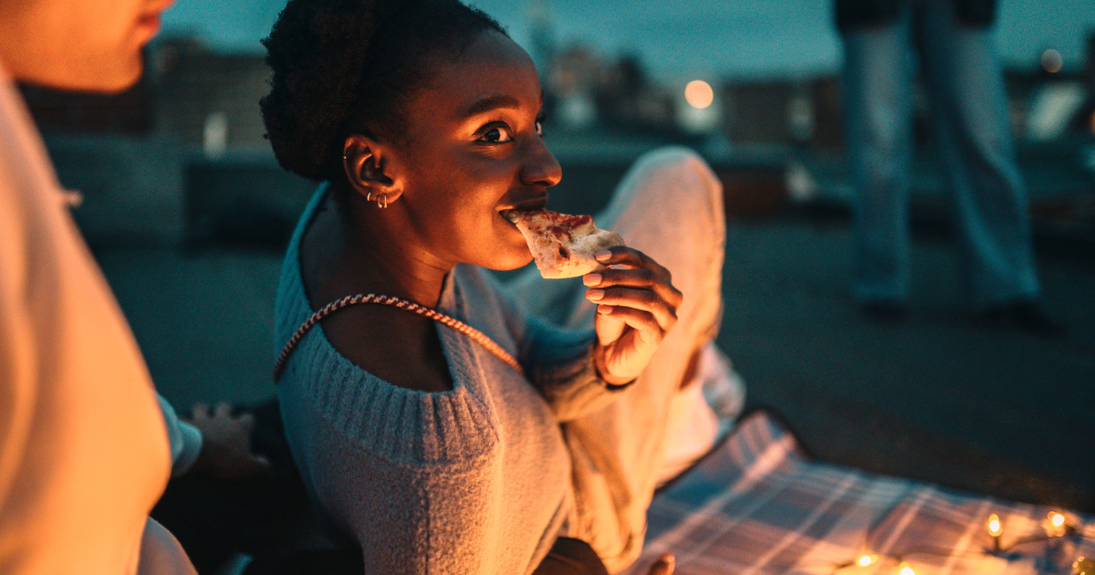 foto van een vrouw die laat op de avond pizza eet in het park