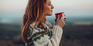 foto van een vrouw die gedachteloos een kop koffie drinkt en daarvan geniet