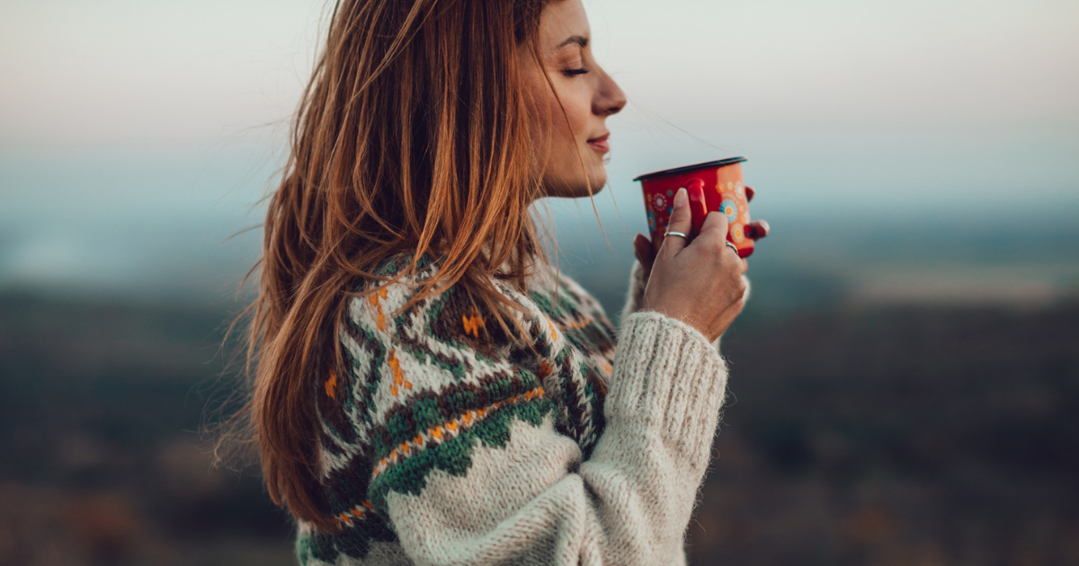 foto van een vrouw die gedachteloos een kop koffie drinkt en daarvan geniet