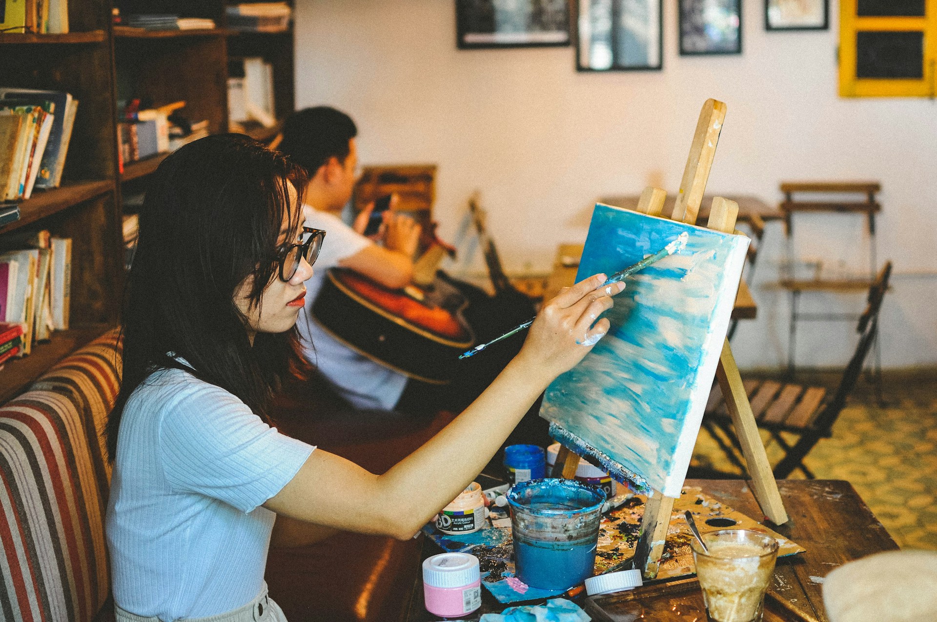 Dame in een atelier die een landschap aan het schilderen is.