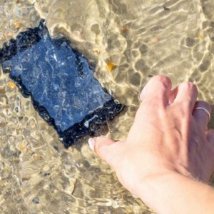 Telefoon die in de zee ligt en hand die hem probeert te pakken.