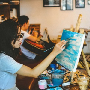 Dame in een atelier die een landschap aan het schilderen is.